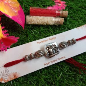 PREMIUM SILVER RAKHI WITH SILVER PEARLS AND RED THREAD.